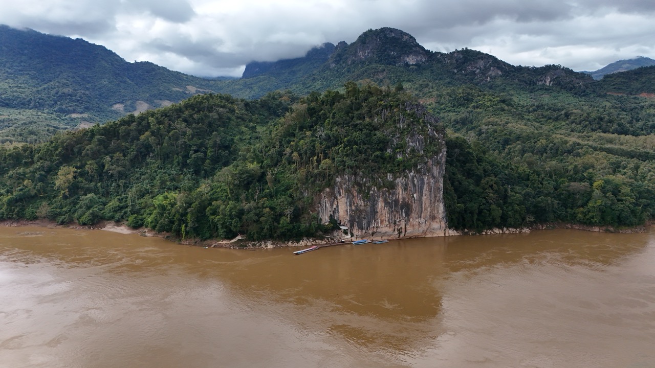 Limestone cliff above the Mekong River in Laos — the landscape you cross the border to ride